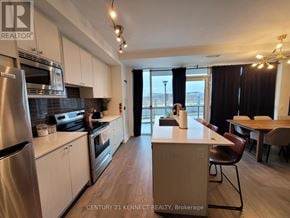 Toronto (Downsview-Roding-Cfb) townhouse for rent - A kitchen with white cabinets and a stainless steel refrigerator.
