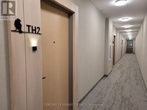 Toronto (Downsview-Roding-Cfb) townhouse for rent - A hallway with a door labeled "TH2" and a brokerage logo.