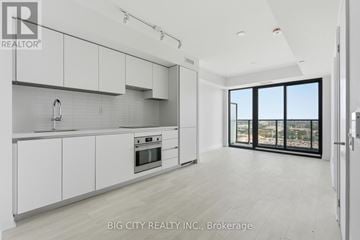 Toronto (Thorncliffe Park) condo for rent - A modern kitchen with white cabinets and a large window.