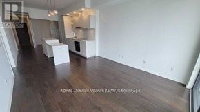 Toronto (Waterfront Communities) condo for rent - A spacious room with wooden floors and white walls, featuring a kitchenette with a sink and a refrigerator.