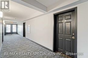 Milton (De Dempsey) condo for rent - A hallway with a black door and a sign that says RE/MAX REALTY SPECIALISTS INC., Brokerage.
