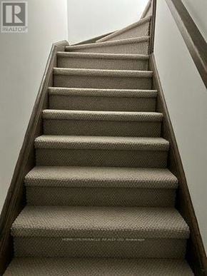 Toronto (New Toronto) townhouse for rent - A beige carpeted staircase with a wooden handrail.