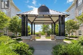 Milton (Wi Willmott) condo for rent - A gazebo-like structure is surrounded by greenery and sits in front of apartment buildings.