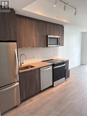 Milton (Cb Cobban) condo for rent - A modern kitchen with dark wood cabinets and stainless steel appliances.
