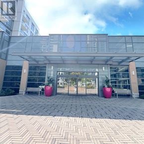 Toronto (Henry Farm) condo for rent - A modern building entrance with glass doors and two large pink planters.