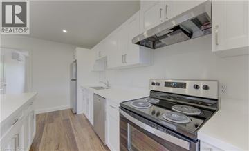 Kitchener apartment for rent - A modern kitchen with white cabinets and a stainless steel stove.