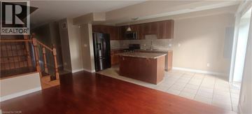 Guelph townhouse for rent - A kitchen with brown cabinets and a black refrigerator.