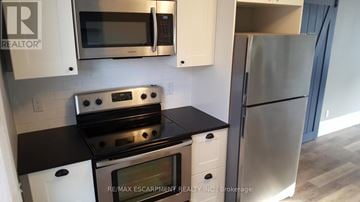 Hamilton (Gibson) multi-family for rent - A kitchen with a stove top oven and microwave above it.