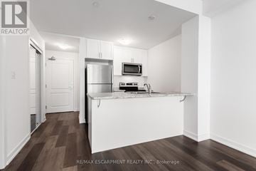 Hamilton (Waterdown) condo for rent - A kitchen with white cabinets and a white island with a microwave on top.