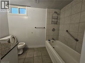 Hamilton apartment for rent - A bathroom with a toilet, tub, and window.