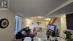 Hamilton (Waterdown) townhouse for rent - A living room with a couch, a coffee table, a TV, and a staircase.