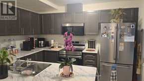 Hamilton (Waterdown) townhouse for rent - A kitchen with a refrigerator, sink, and cabinets.
