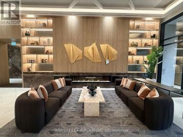 Vaughan (Vaughan Corporate Centre) condo for rent - A modern living room with a long black couch and a wooden wall.