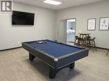 Lloydminster apartment for rent - A pool table in a room with a television and a door leading to a dining area.