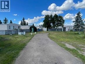 Lloydminster apartment for rent - A gravel path leads through a grassy area to a cluster of houses.