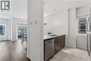 Stoney Creek townhouse for rent - A modern kitchen with stainless steel appliances and a dining area with a table and chairs.