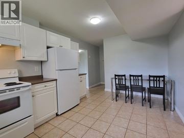 Coquitlam apartment for rent - A kitchen with white appliances and a dining table with chairs.