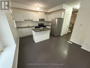 Ajax (Central) townhouse for rent - A kitchen with white cabinets and a black stove top oven.
