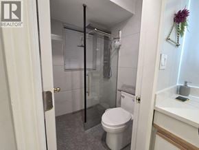 Coquitlam apartment for rent - A white toilet is in a small bathroom with a glass shower door.