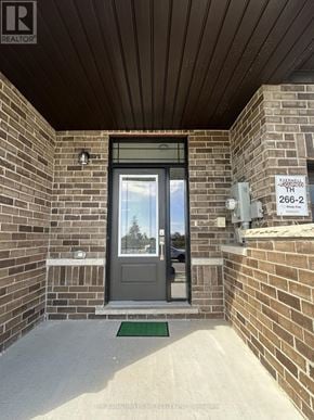 Barrie townhouse for rent - The entrance to a building with a glass door and a brick wall.