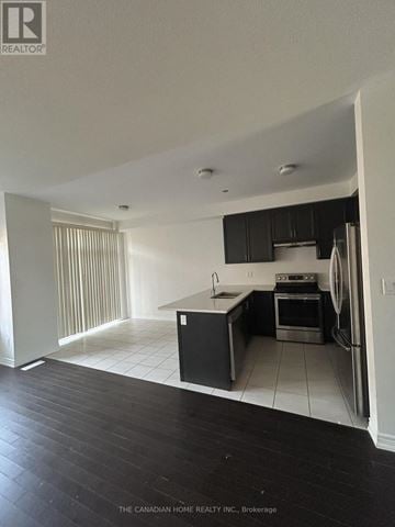 Barrie townhouse for rent - A kitchen with black cabinets and a white fridge.
