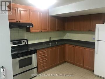 Brampton (Bram East) apartment for rent - A kitchen with wooden cabinets and a black countertop.