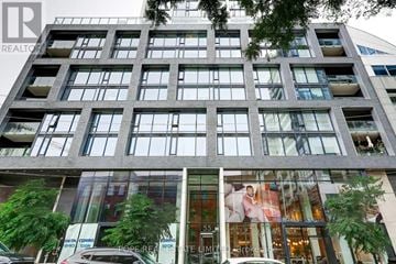 Toronto (Moss Park) condo for rent - A tall building with a glass window in front of a tree.