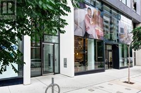 Toronto (Moss Park) condo for rent - A building with a glass facade and a tree in front of it.