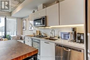 Toronto (Moss Park) condo for rent - A modern kitchen with stainless steel appliances and white cabinets.
