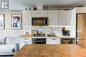 Toronto (Moss Park) condo for rent - A modern kitchen with a wooden table and a refrigerator.
