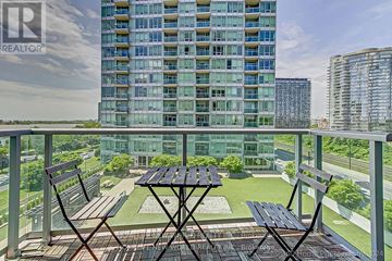 Toronto (South Parkdale) condo for rent - A balcony with a table and chairs overlooks a large building and a body of water.
