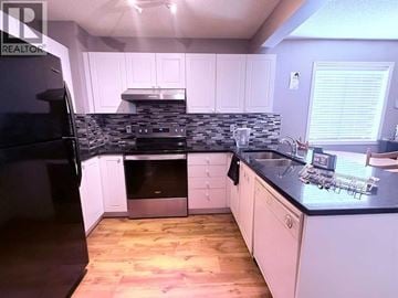 Calgary apartment for rent - A kitchen with a black fridge and a black counter top.