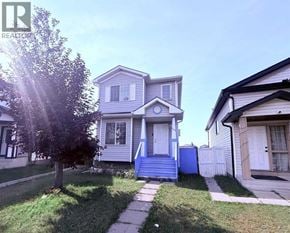 Calgary apartment for rent - A house with a blue door and a tree in front of it.