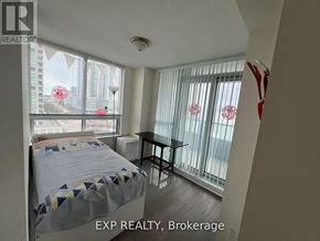 Toronto (Bendale) condo for rent - A bedroom with a bed, table, and a window with a view of a cityscape.