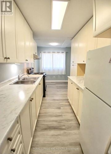 Niagara Falls (Downtown) fourplex for rent - A kitchen with white cabinets and a marble countertop.