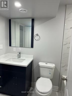 Bradford West Gwillimbury (Bradford) apartment for rent - A white toilet with a blue dot on the lid is in a bathroom with a white sink and a mirror.