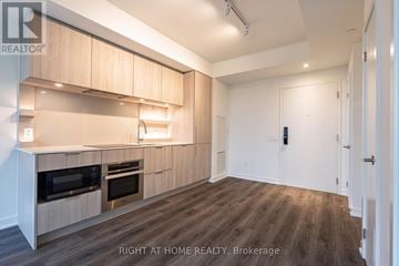 Mississauga (Port Credit) condo for rent - A modern kitchen with wooden cabinets and a white door.