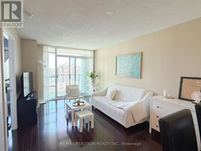 Toronto (Willowdale East) condo for rent - A living room with a white couch and a painting on the wall.