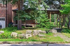 Toronto (Birchcliffe-Cliffside) apartment for rent - A house with a porch surrounded by rocks and trees.