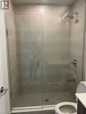 Toronto (Waterfront Communities) condo for rent - A bathroom with a toilet, a glass shower stall and a white door.