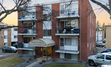 Edmonton apartment for rent - A red brick apartment building with a balcony and a sign that says Woodland Manor.