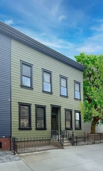 Brooklyn apartment for rent - A two-story house with a green siding and a black iron fence.