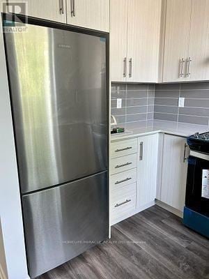 Toronto (New Toronto) townhouse for rent - A stainless steel refrigerator in a kitchen with wooden cabinets.