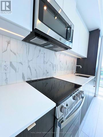 Toronto (Annex) condo for rent - A modern kitchen with a black stove top oven and white countertops.