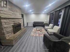 Clarington (Courtice) apartment for rent - A living room with a stone fireplace and grey couches.