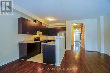 Caledon townhouse for rent - A kitchen with dark wood cabinets and white appliances.