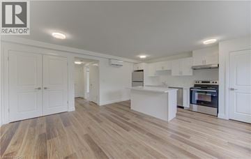 Kitchener apartment for rent - A spacious kitchen with white cabinets and a wooden floor.