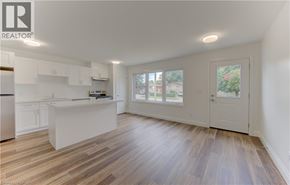 Kitchener apartment for rent - A spacious kitchen with white cabinets and a wooden floor.