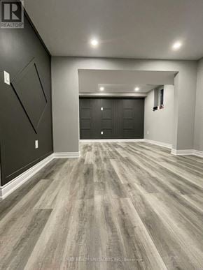 Barrie (Georgian Drive) apartment for rent - A spacious room with wood flooring and a black door at the end.