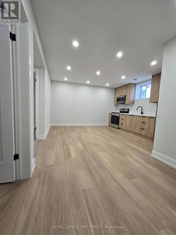 Niagara Falls (Brown) apartment for rent - A spacious room with wooden flooring and a kitchenette in the corner.